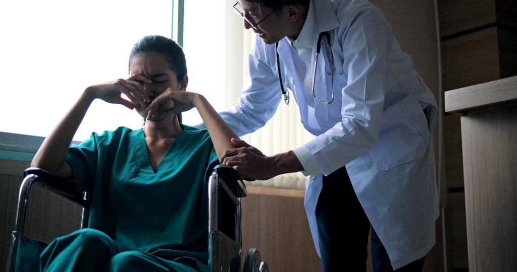 Young Asian woman depressed in a wheelchair while doctor comforts her